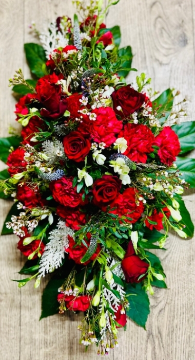 A 3 ft funeral spray with a selection of red roses and carnations enhanced with a selection of winter green foliage