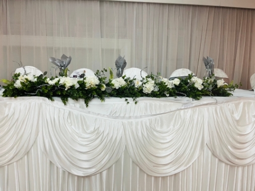 A faux garland of flowers, suitable for top table or stairways etc, approx  5ft long and enhanced with foliage and some silver items to add to the overall design