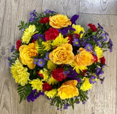 A fresh flower colourful arrangement suitable for sympath or remberance with red roses and seasonal flowers and foliage